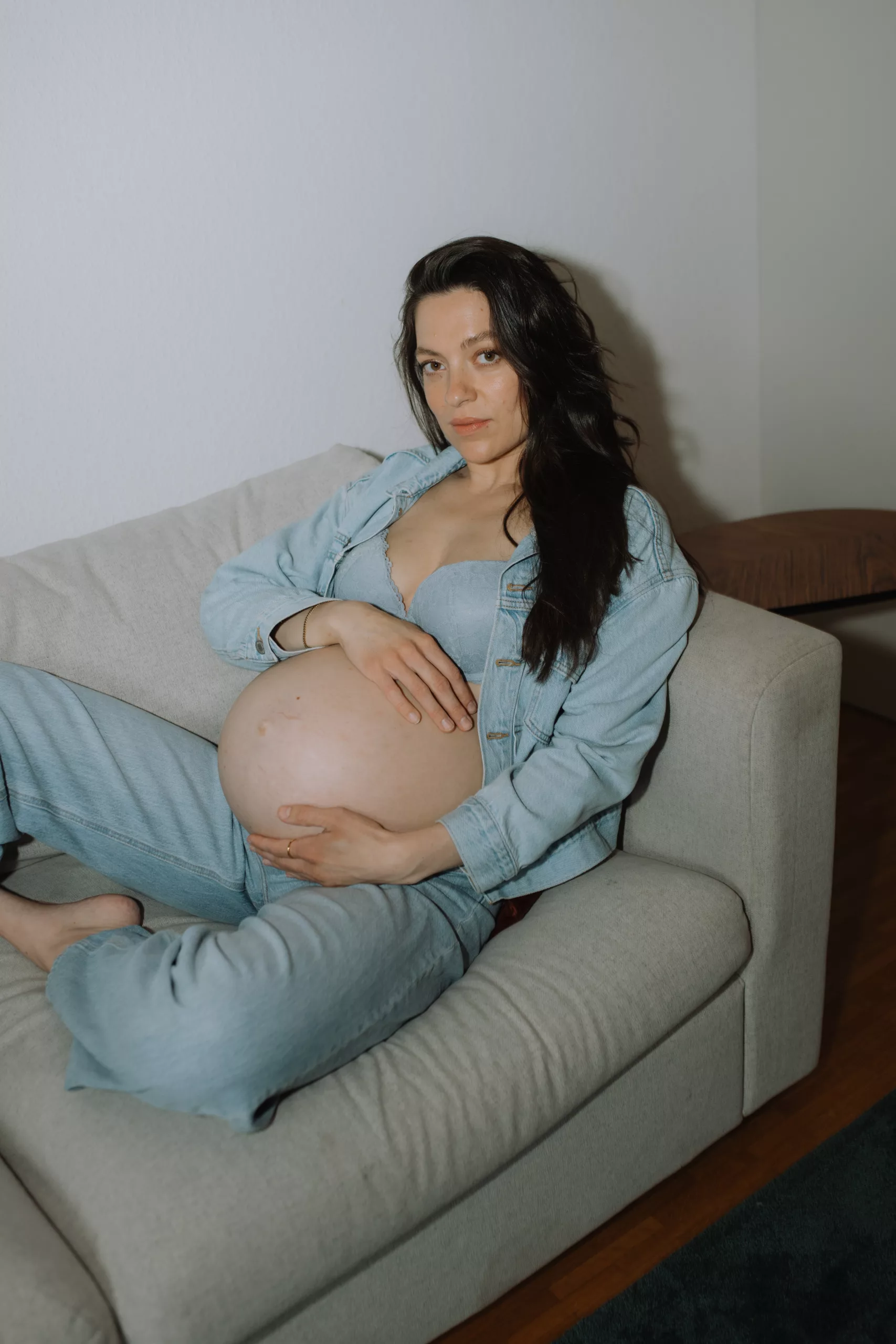 Schwangere Frau liegt auf Sofa, mit Blitz fotografiert