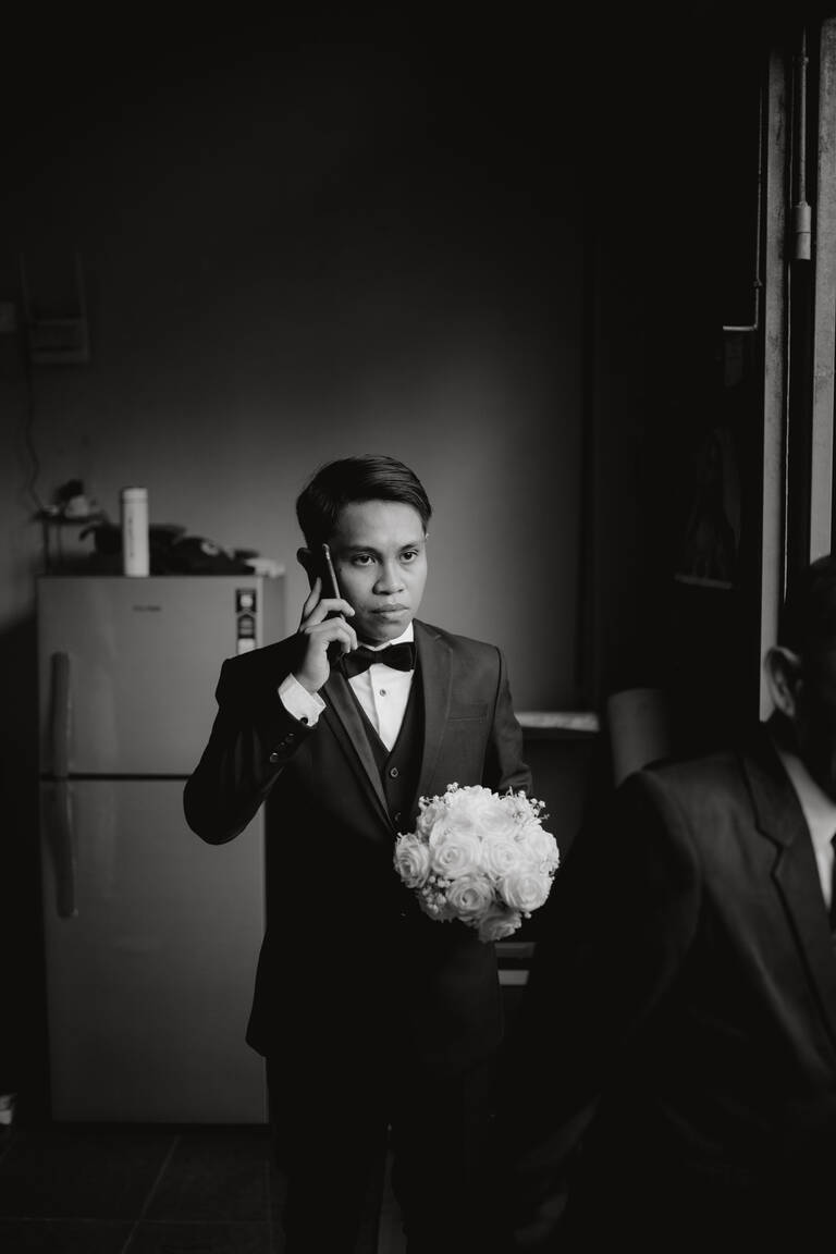 Indonesien, Bräutigam ist am Telefon, steht mit Blumen in der Hand und wird emotional