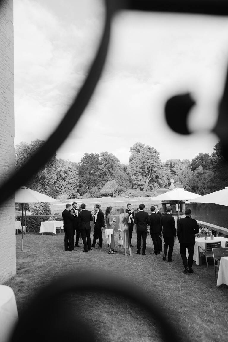 Hochzeitsgesellschaft steht im Garten von Schloss Dyck, alle sind im Frack und sehr schick gekleidet, Black Tie dress code