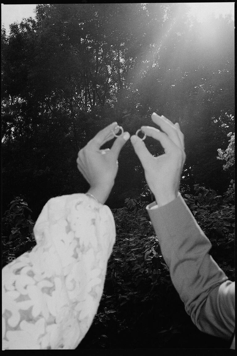 Brautpaar zeigt Ringe in die Höhe, Gegenlicht, analoge Aufnahme