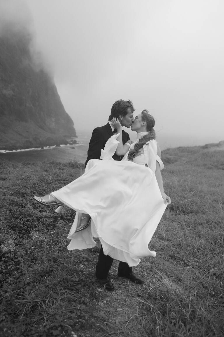 Brautpaar, Bräutigam hebt Braut hoch, editorial, steht vor dramatischer Kulisse in Madeira