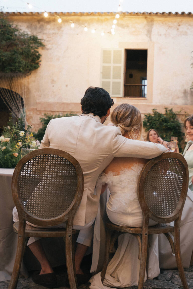 Hochzeitspaar liegt sich in den Armen, Abendstimmung von einem mit Blumen geschmückten Hochzeitstisch in einer Finca auf Mallorca, Son Burget Villa